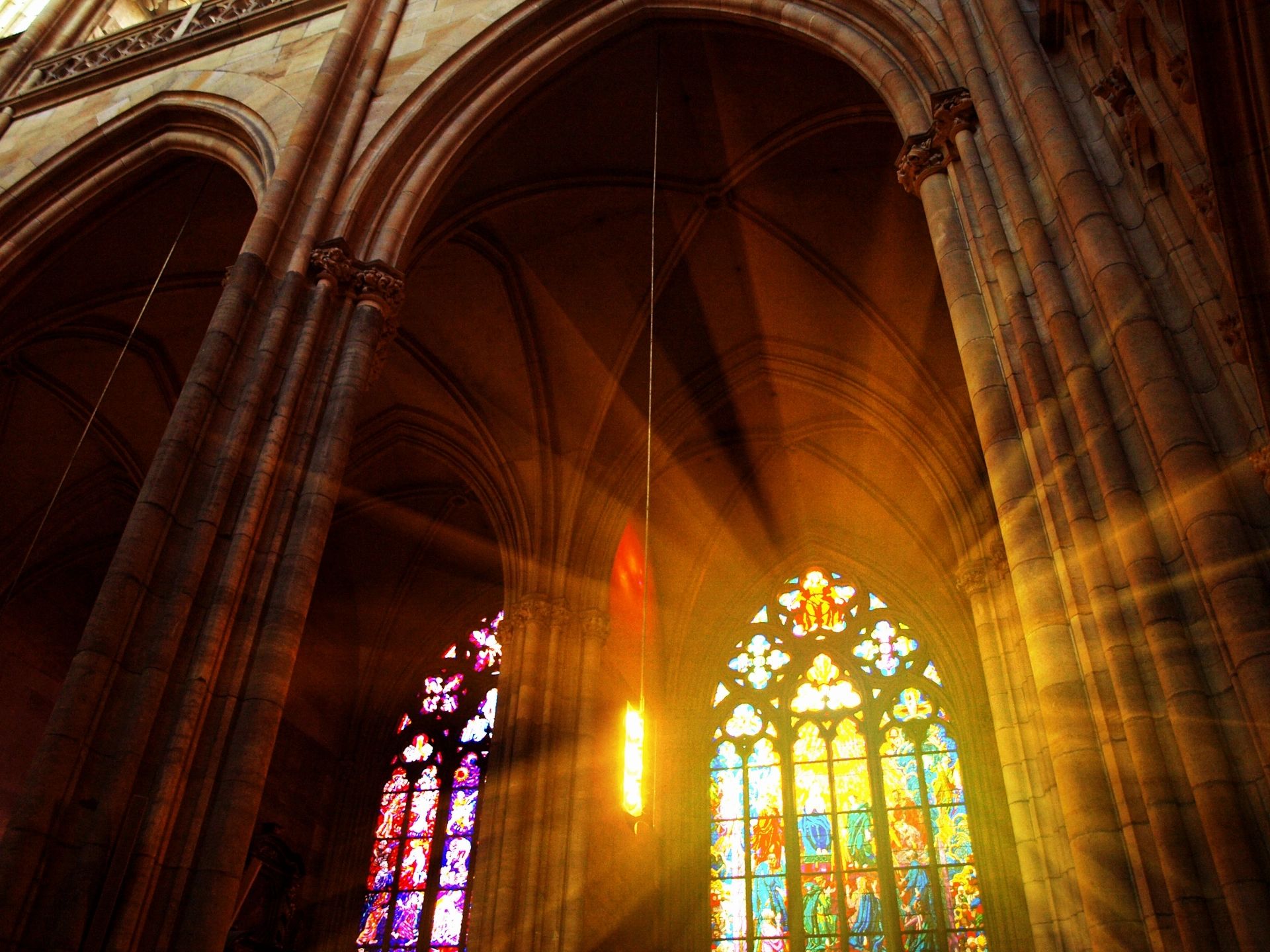 Warm sunlight streaming through the stained-glass windows of a church