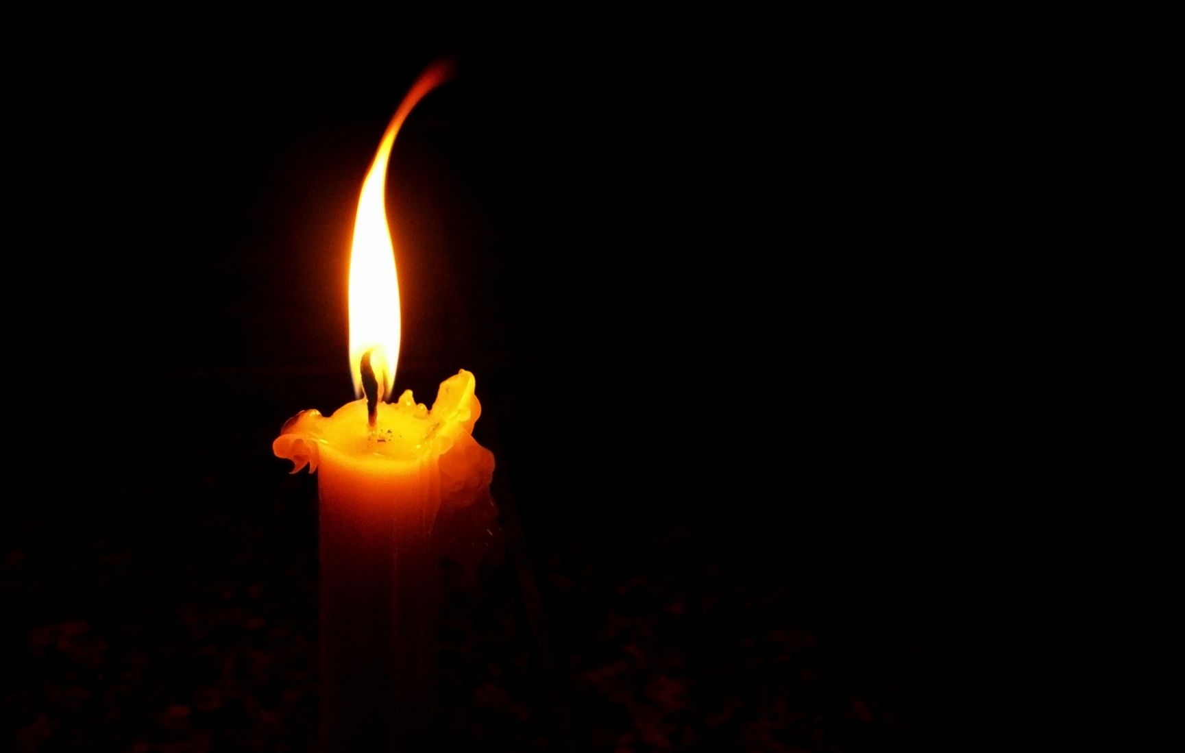 A single candle flame burning against a dark background